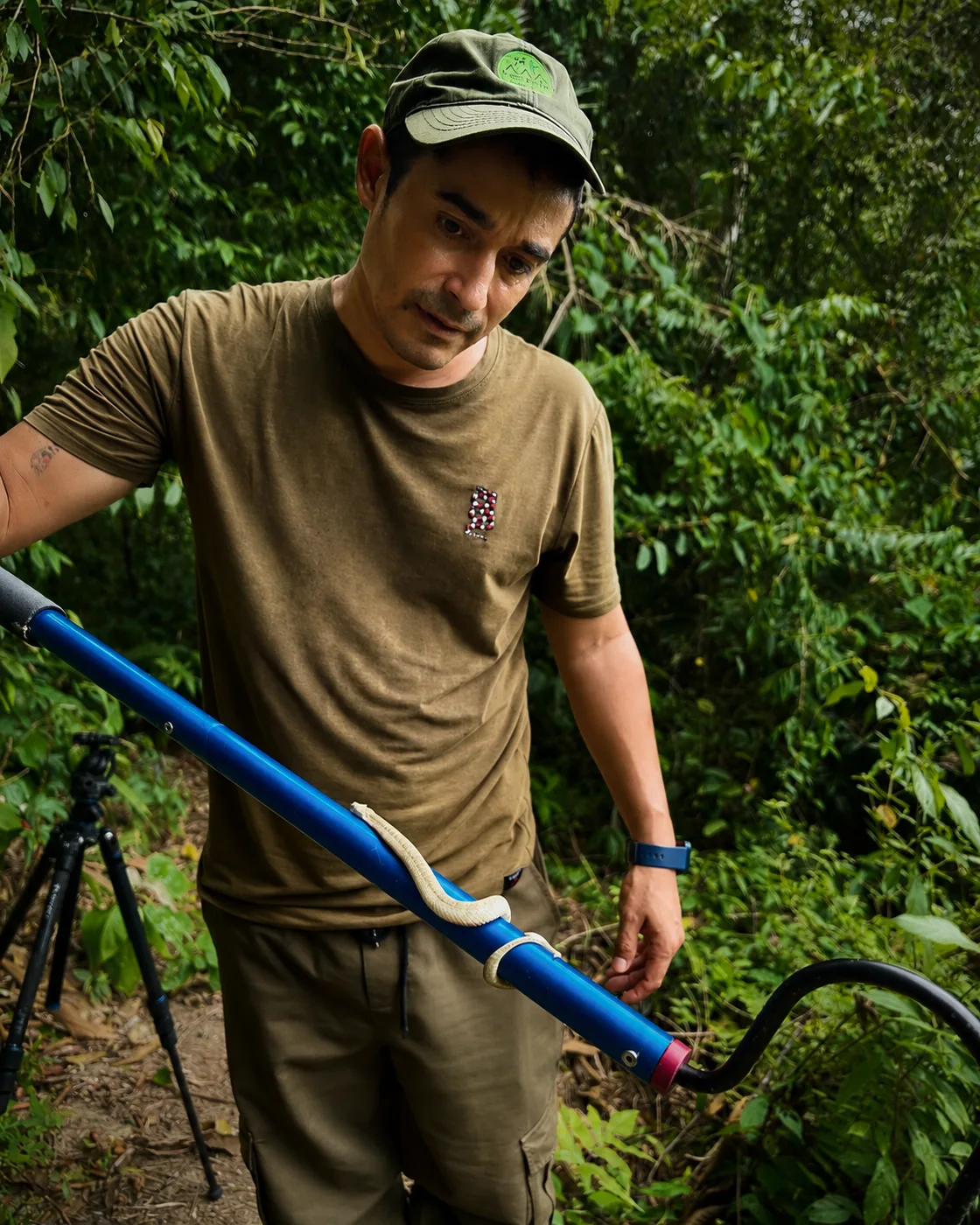 Abel Batista en el campo con un gancho herpetológico y una pequeña culebra